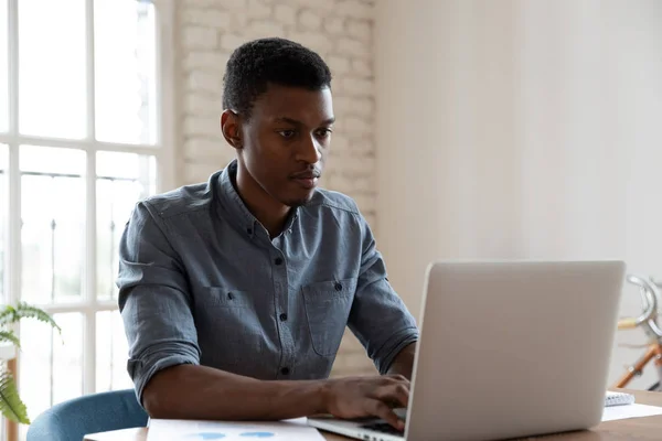 Serious African American businessman using laptop, working on project — Stock Photo, Image