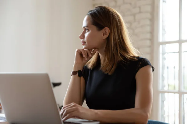 Mujer de negocios reflexiva mirando a la distancia, utilizando el ordenador portátil, la estrategia de ponderación — Foto de Stock