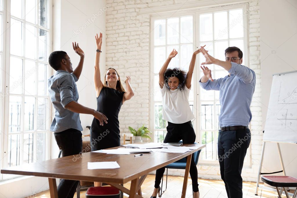 Happy business people celebrating success, dancing at meeting in boardroom