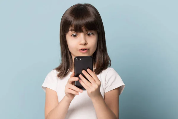 Huvudskott studio porträtt förvånad unge flicka tittar på smartphone-skärmen. — Stockfoto