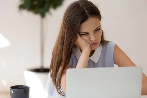 Vrouw voelt verveling zitten aan bureau kijken naar laptop scherm — Stockfoto