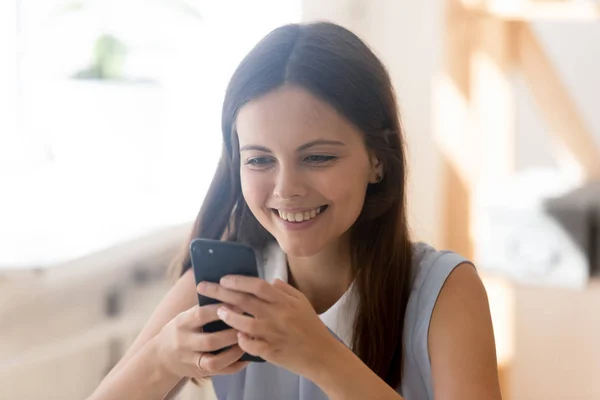 Attraente giovane donna sorridente guardando lo schermo dello smartphone — Foto Stock