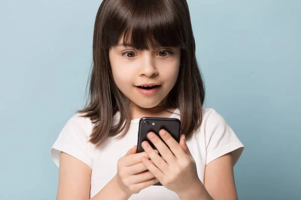 Närbild upphetsad förskola flicka som håller mobiltelefon. — Stockfoto