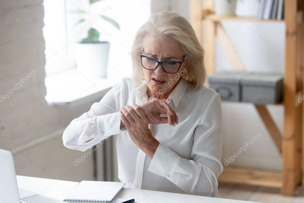 Mature businesswoman touching hand feeling wrist pain