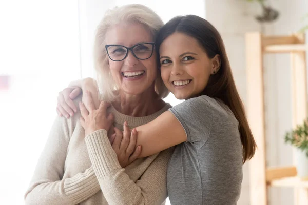 Middle-aged mom embraces and grown up daughter hugging indoors — Stock Photo, Image