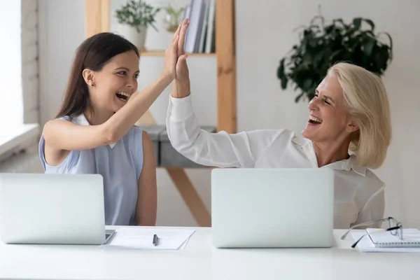 Different generations women colleagues giving high five celebrating common success — ストック写真