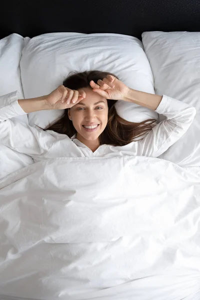 Potret vertikal wanita bahagia berbaring di bantal lembut di tempat tidur — Stok Foto