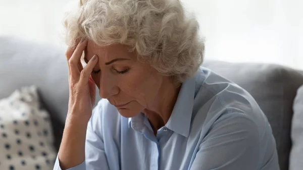 Close up unhappy older woman touching forehead, suffering from headache — Stock Photo, Image