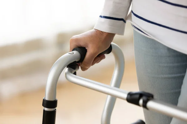 Close up disabled older woman holding hand on walker