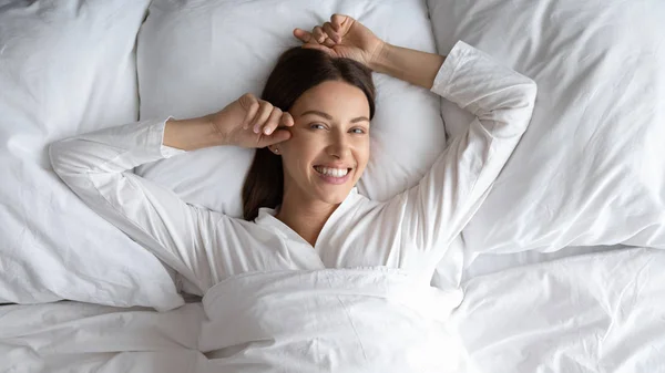 Cabeça tiro sorrindo bela mulher deitada em cama confortável — Fotografia de Stock