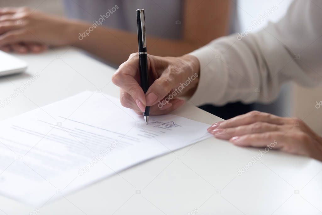 Close up view female hand signing contract legal document