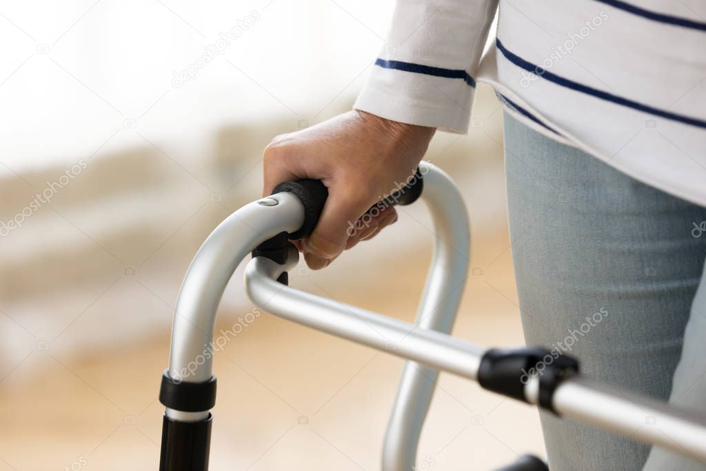 Close up disabled older woman holding hand on walker