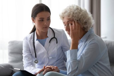 Bakıcı doktor, evde üzgün yaşlı kadına destek oluyor.