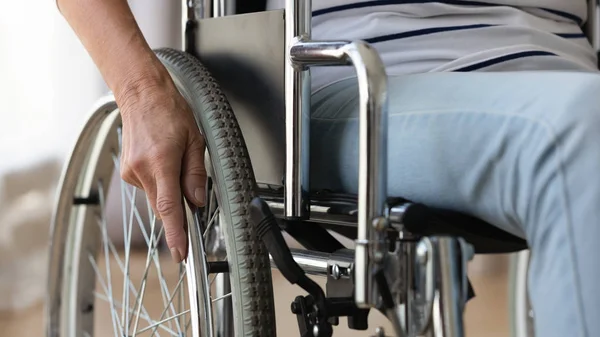 Close up disabled older woman sitting in wheelchair, touching wheels — Stock Photo, Image