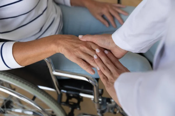 Vista dall'alto close up caregiver holding disabili donna anziana mano — Foto Stock