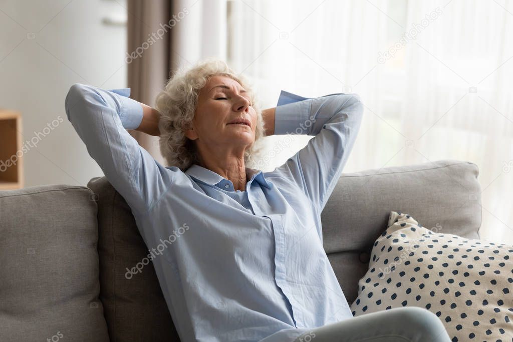 Older woman relaxing at home, sleeping on comfortable couch
