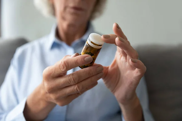 Cerca de la mujer mayor sosteniendo la botella con pastillas, instrucción de lectura — Foto de Stock