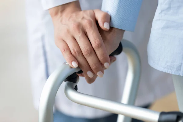 Close up caregiver tenendo la mano della donna anziana sul camminatore — Foto Stock