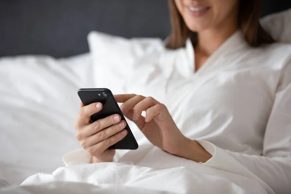Close up sorrindo mulher usando telefone, sentado na cama — Fotografia de Stock