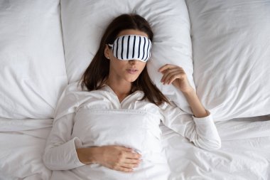 Yatakta uzanmış, maske takan güzel bir kadın.