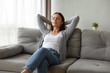 Evdeki rahat kanepede dinlenen güzel genç bir kadın.