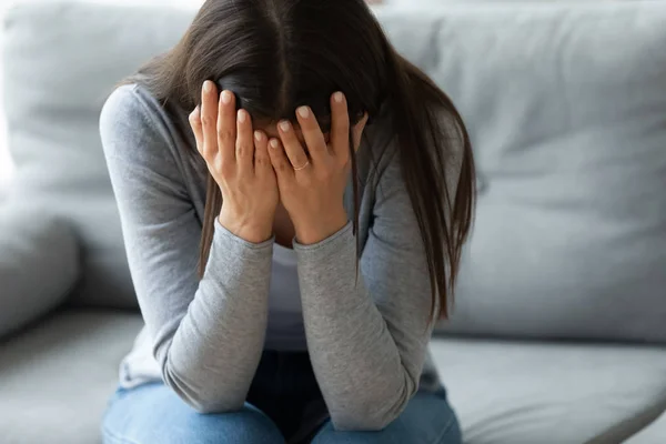 Несчастная молодая женщина закрывает лицо руками, плачет в одиночестве — стоковое фото