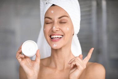 Yüz kremi tutan komik, güzel bir kadın.