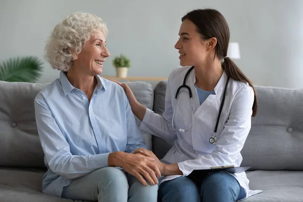 Szczęśliwa starsza kobieta rozmawia z przyjaznym lekarzem podczas wizyty — Zdjęcie stockowe