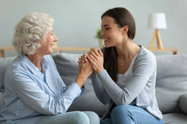 Smiling granddaughter holding grandmother hands, expressing love and support — Stock Photo, Image