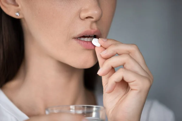 Close up woman holding white pill and glass of water — Stock Photo, Image