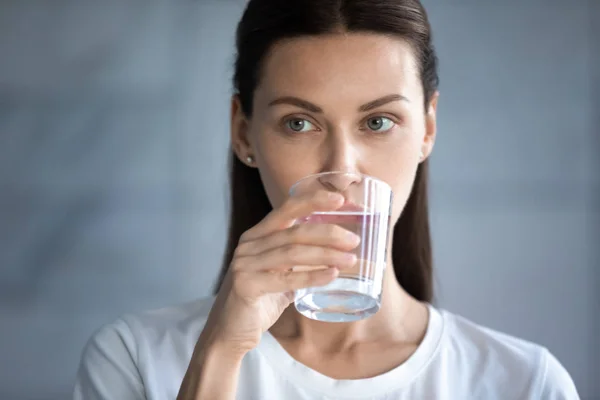 Cabeça tiro mulher bonita beber água mineral limpa, segurando vidro — Fotografia de Stock