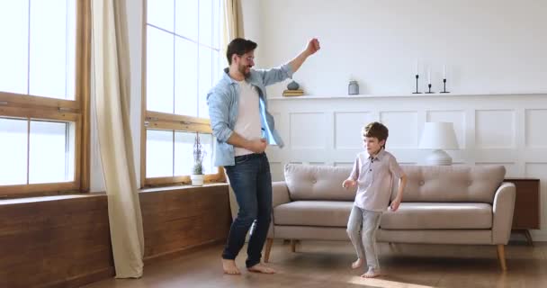 Förskolebarn son dansar hoppa med bekymmerslös far hemma — Stockvideo
