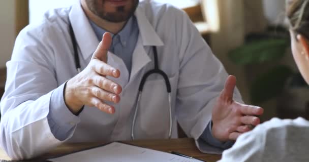 Врач мужского пола консультирует пациентку с рукопожатием на приеме у врача, крупным планом — стоковое видео