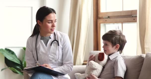 Профессиональная женщина врач поговорить с ребенком мальчик пациент держать игрушку — стоковое видео