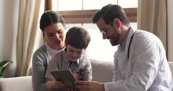 Amistoso pediatra masculino consultando niño niño paciente con tableta digital — Vídeos de Stock