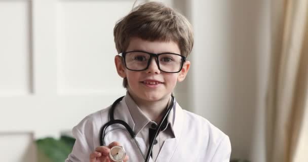 Child boy wear white coat holding stethoscope looking at camera — Stock Video