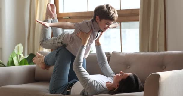 Divertido niño preescolar jugando juego de avión con la madre en el sofá — Vídeos de Stock