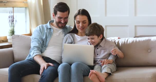 Молодые родители с маленьким сыном наслаждаются онлайн-покупками на ноутбуке — стоковое видео