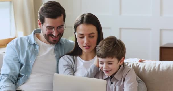Ontspannen familie van drie met behulp van laptop zitten op de bank — Stockvideo