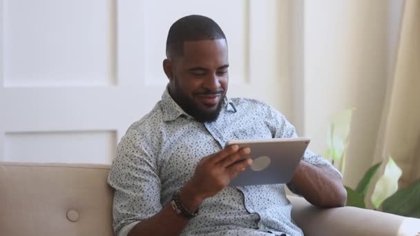 Glimlachende biraciale jonge man met behulp van digitale tablet. — Stockvideo
