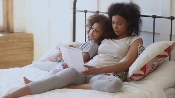 Aangename biracial vrouw het lezen van boek aan dochter. — Stockvideo