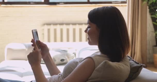 Jovem mulher atraente descansando no sofá acolhedor conversando online . — Vídeo de Stock