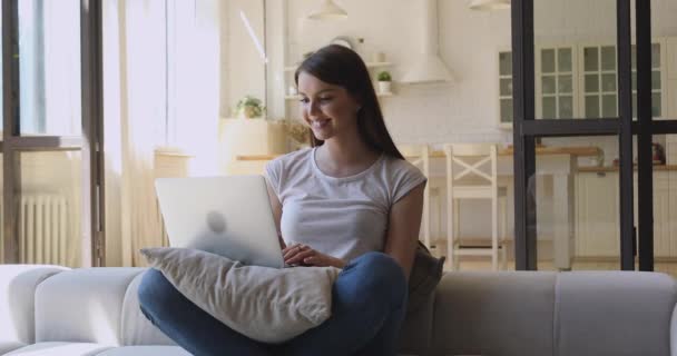 Glückliche junge Frau entspannt auf Sofa mit Computer. — Stockvideo