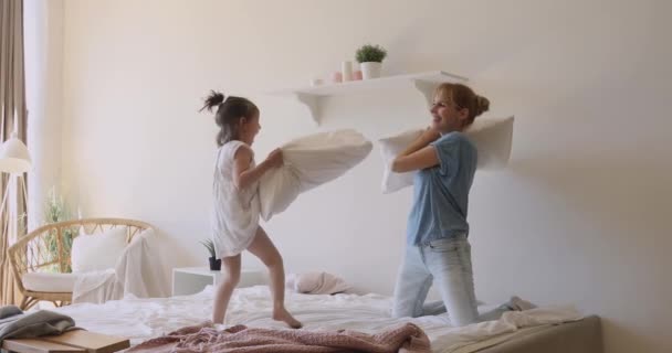 Alegre familia luchando con almohadas en la cama . — Vídeos de Stock