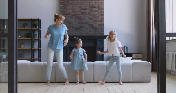 Mutlu genç bir kadın oturma odasında çok mutlu kızlarıyla dans ediyor.. — Stok video