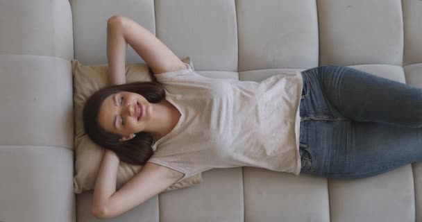 Lykkelig ung kvinde liggende på stor komfortabel sofa, dagdrømmer . – Stock-video