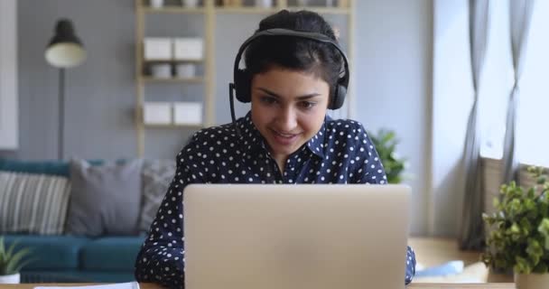 Smiling indian woman wear wireless headset video calling on laptop — Stock Video