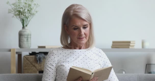 Mujer de mediana edad lectura relajante libro sentarse en el sofá — Vídeo de stock