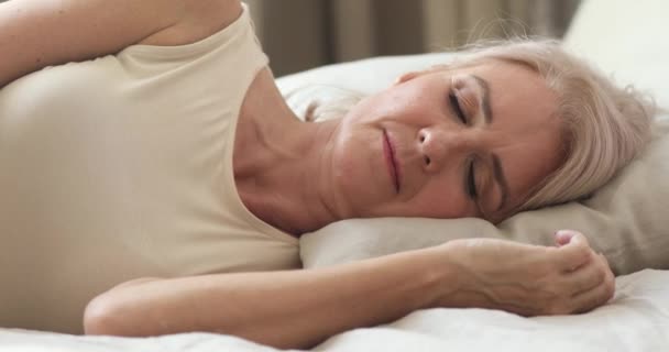 Спокойная спокойная зрелая женщина спит хорошо в удобной постели — стоковое видео