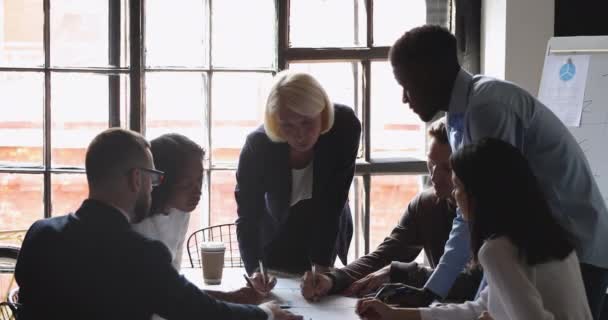 Серйозна різноманітна бізнес-команда зі старшим лідером, який аналізує документи разом — стокове відео